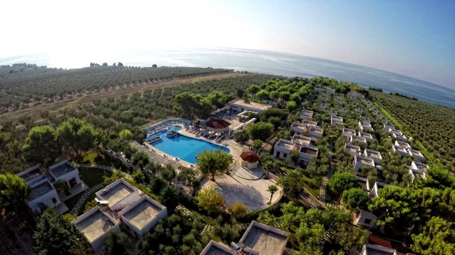 Villaggio con piscina e case in mezzo al verde, vicino al mare.