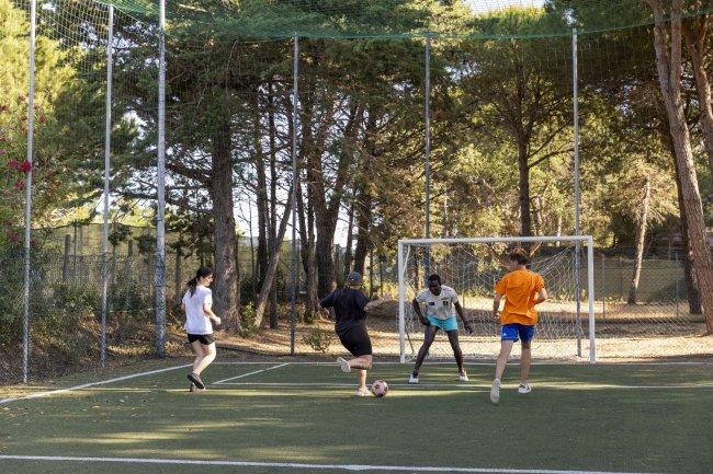 Gruppo di ragazzi gioca a calcio su un campo all'aperto.