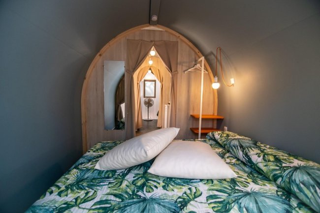 Interno di una tenda con letto e coperte tropicali.