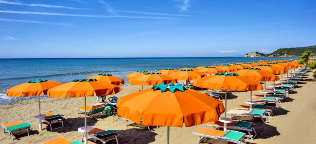 Spiaggia con lettini e ombrelloni arancioni.