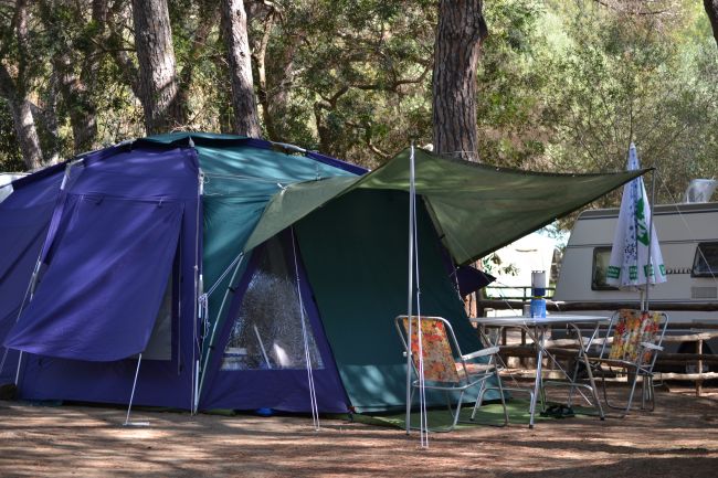 Una tenda blu con telo verde e sedie da campeggio.