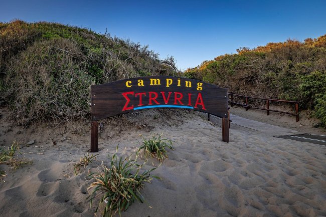 Ingresso camping con cartello su spiaggia.