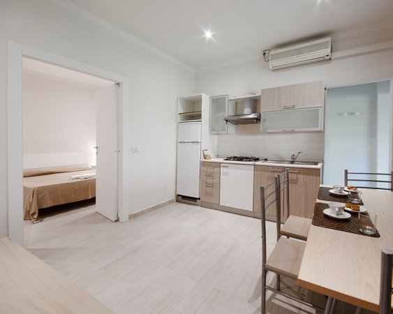 Cucina moderna con tavolo da pranzo e camera da letto annessa.