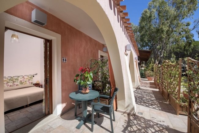 Patio con tavolino, sedie e ingressi a camere.