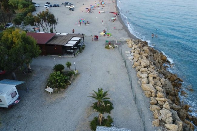 Spiaggia con bar, rocce e camper.