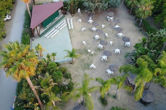 Vista dall'alto di area esterna con sedie e tavoli bianchi sotto ombrelloni.