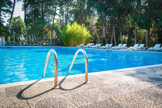 Piscina blu circondata da lettini bianchi.