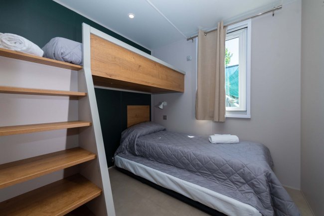 Cameretta con letto a castello e scale in legno.