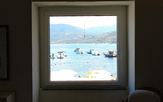 Vista mare da una finestra con barche.