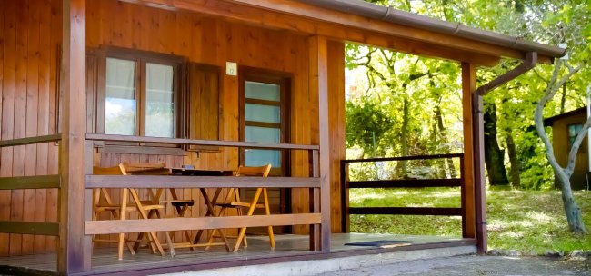 Veranda in legno con tavolo e sedie.