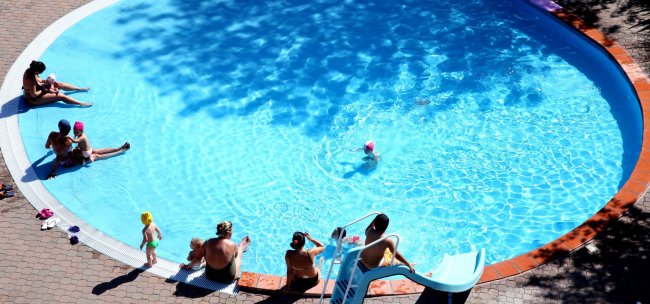 Piscina rotonda con bagnanti e scivolo.