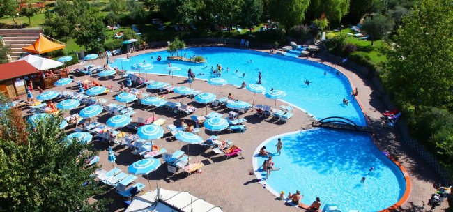 Ampia piscina con lettini e ombrelloni.