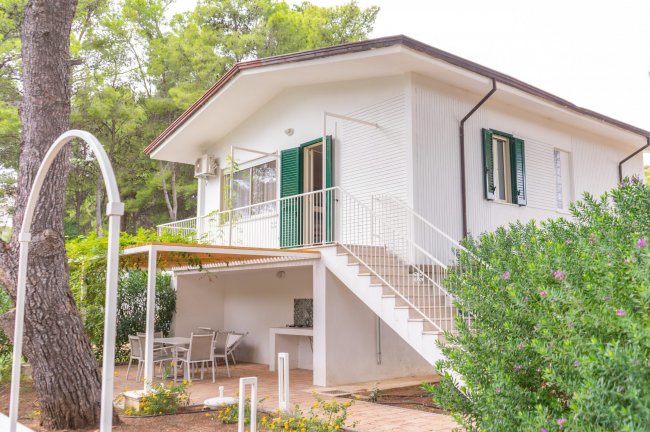 Villetta bianca a due piani con veranda e giardino.