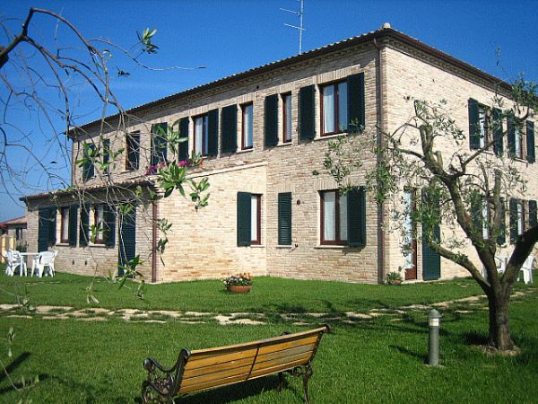 Casa di mattoni con giardino e panchina.