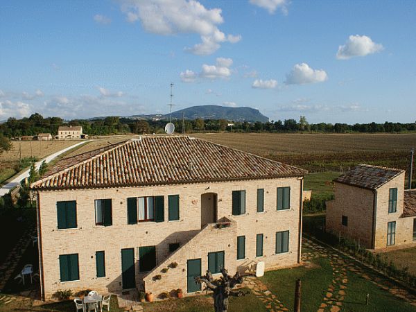 Un casolare in mattoni con tetto in tegole, immerso in un paesaggio di campagna.