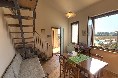 Interno con scala a chiocciola, tavolo, sedie e vista sulla piscina.