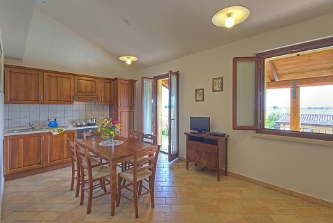Cucina con tavolo apparecchiato, porta aperta e finestra con vista.