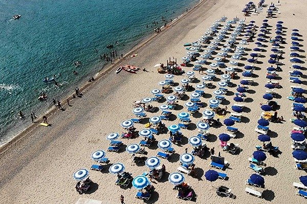 Spiaggia affollata con ombrelloni blu.