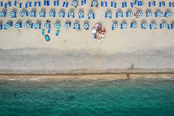 Vista dall'alto di una spiaggia con ombrelloni blu.