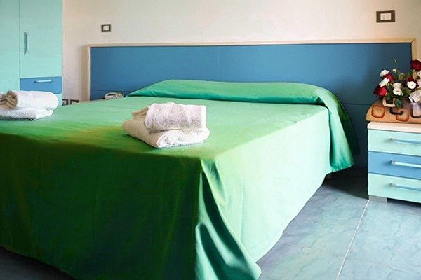 Letto con copriletto verde e asciugamani.