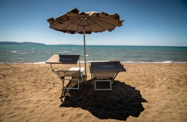 Due lettini con ombrellone su una spiaggia sabbiosa.