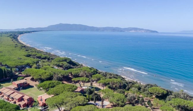 Vista costiera con mare e colline, vegetazione lussureggiante.