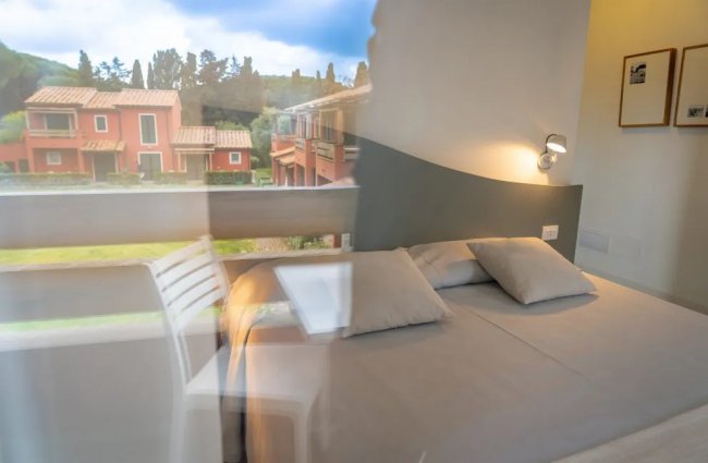 Camera con letto matrimoniale e vista su case rosse all'esterno.