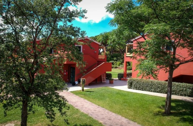 Edifici rossi con tetti in tegole e alberi circostanti.