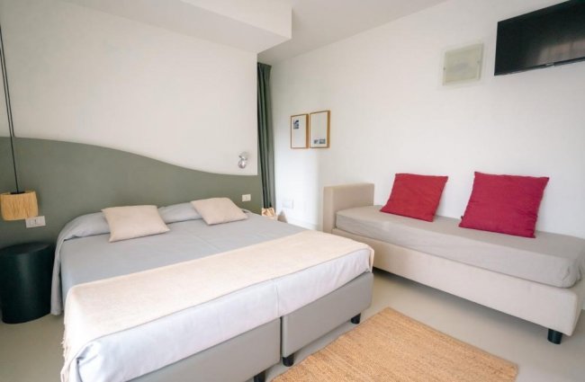 Camera con letto matrimoniale e divano con cuscini rossi.