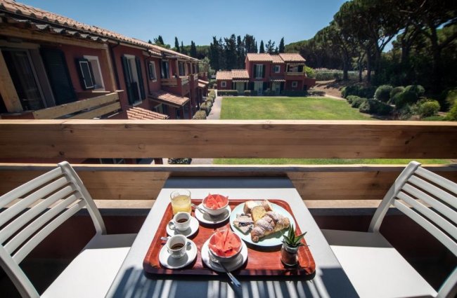 Colazione su terrazza con vista su giardino e palazzi.