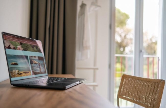 Laptop su scrivania accanto a finestra aperta.