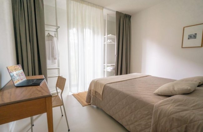 Camera da letto con scrivania, letto doppio e tende.