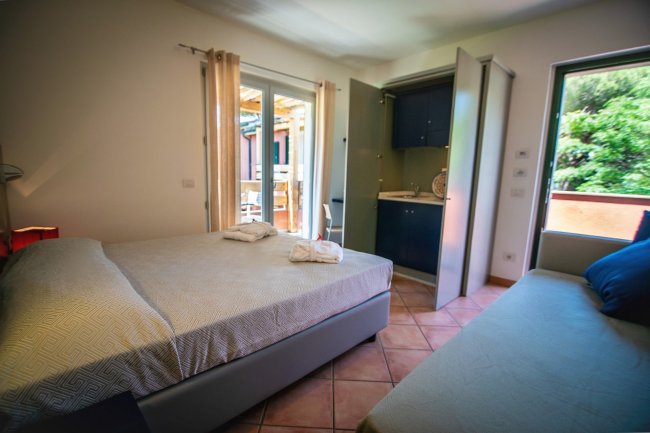 Camera con letto matrimoniale, divano e uscita sul balcone.