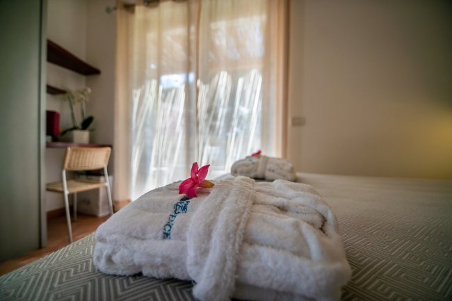 Accappatoio bianco con fiore sul letto.