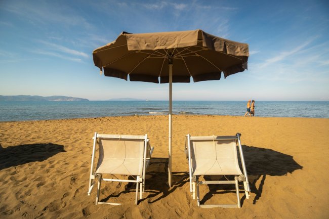 Due sedie a sdraio sotto un ombrellone sulla spiaggia.