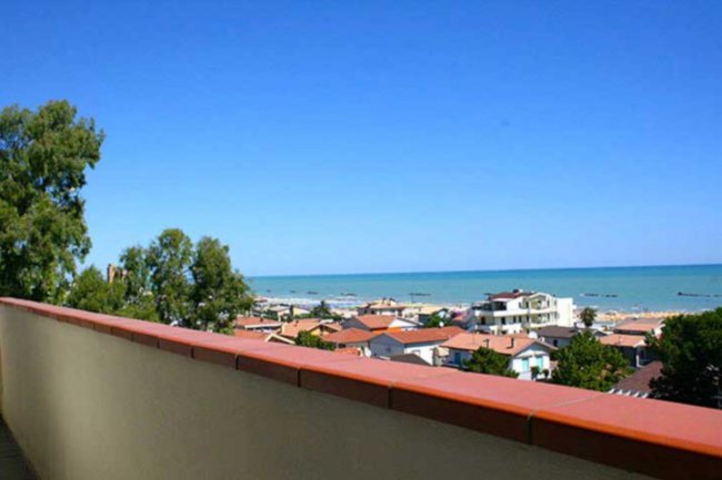 Vista panoramica di case e mare sotto cielo blu.