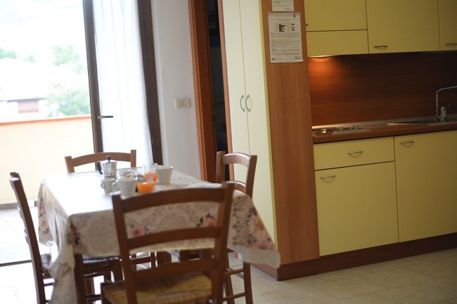 Cucina con tavolo apparecchiato vicino a balcone.