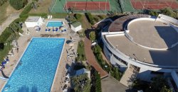 Piscina, solarium e campo da tennis circondati da giardini.