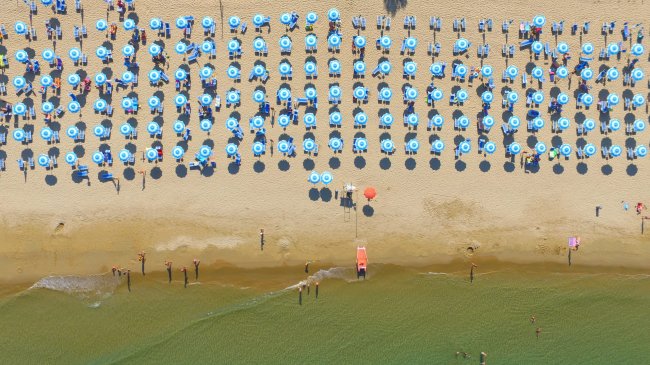 Ombrelloni blu su una spiaggia sabbiosa affollata.