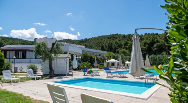 Piccola piscina con sedie a sdraio, sullo sfondo colline.