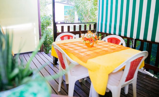 Terrazza con tavolo arancione, sedie bianche.