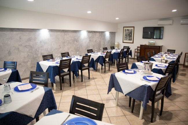 Sala da pranzo con tavoli apparecchiati.