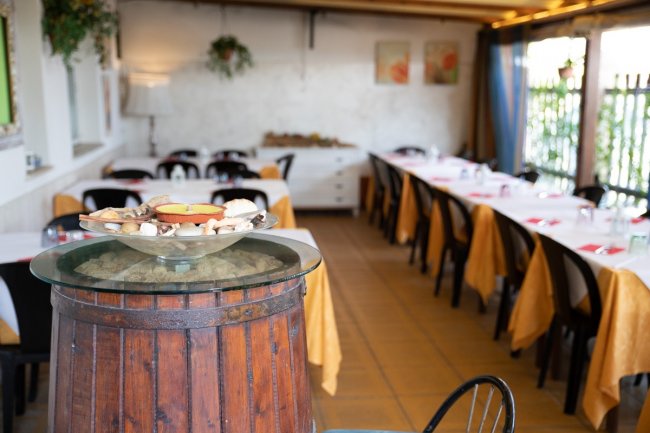 Ristorante con tavoli apparecchiati e barile decorativo.
