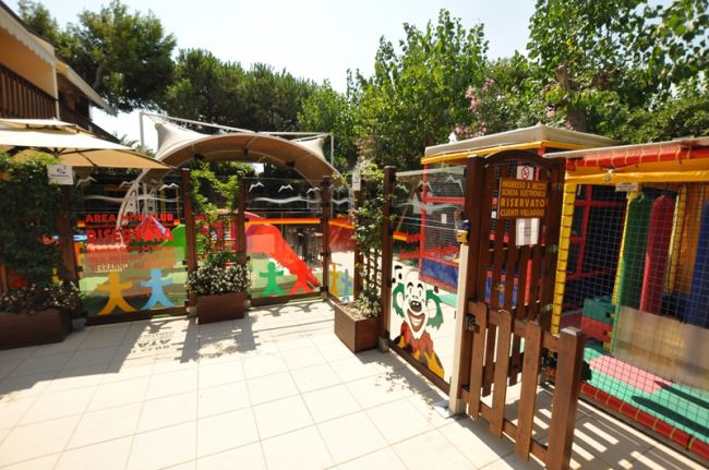 Area giochi all'aperto con scivolo, recinzione colorata e decorazioni vivaci.