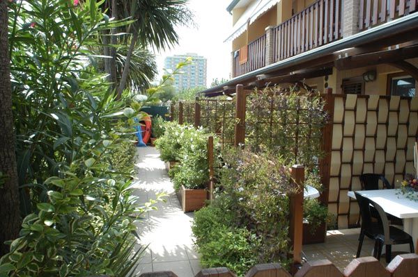 Percorso giardino stretto con siepi e pannelli divisori vicino a un edificio.