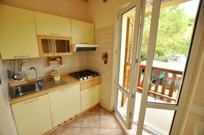 Cucina compatta con mobili gialli e porta aperta verso il balcone.