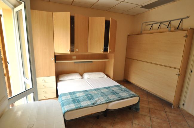 Una camera da letto con un letto a due piazze, armadi di legno chiaro e una coperta a quadri.