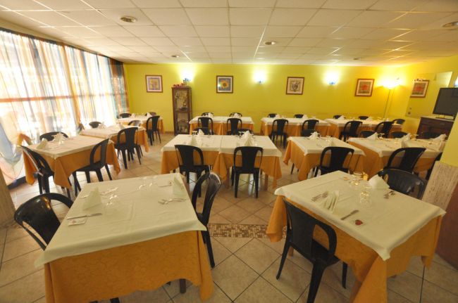 Ristorante con tavoli apparecchiati e sedie nere.