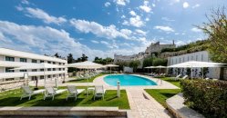 Piscina con ombrelloni bianchi e lettini.