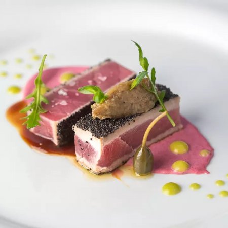 Due filetti di pesce con salsa rosa e guarnizioni verdi.